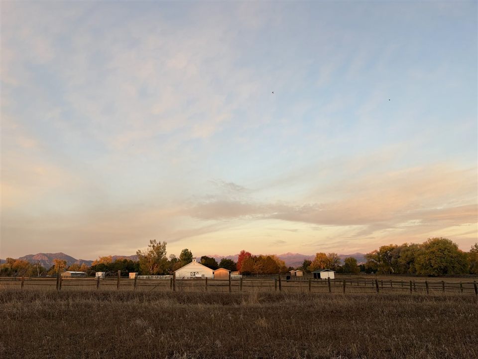 Fields and a white barn at sunset outside Boulder, Colorado, with the Front Range behind